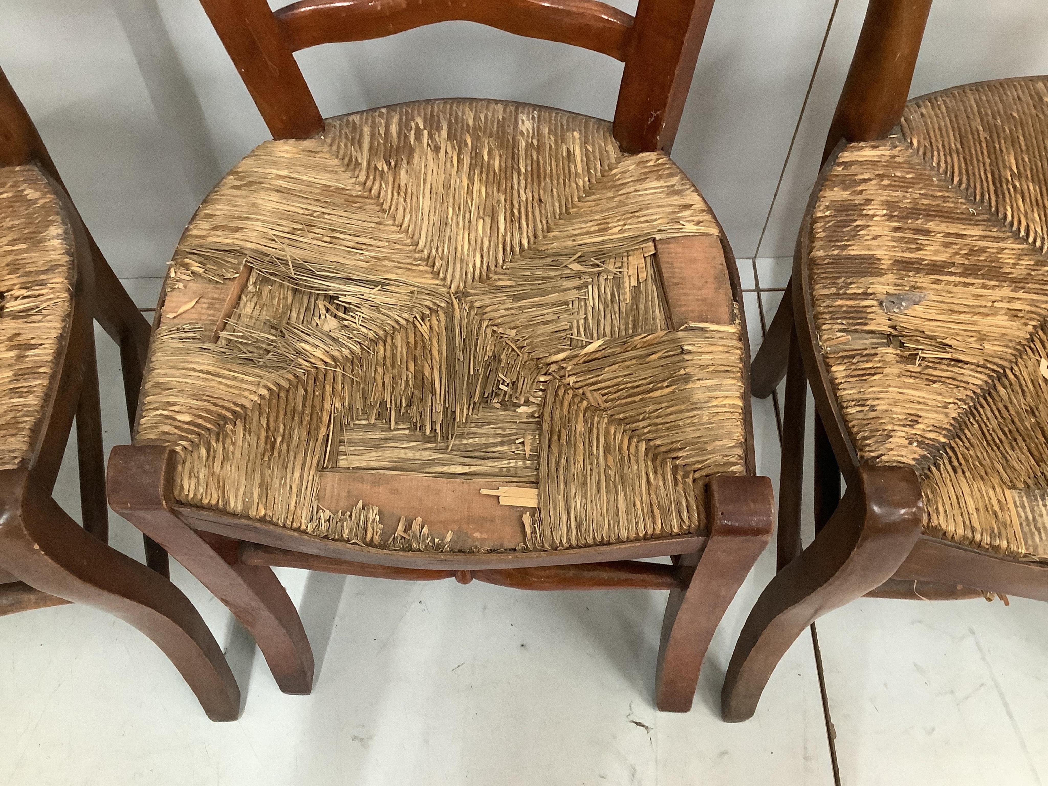 A set of four 19th century French provincial rush seat dining chairs, height 90cm. Condition - poor to fair